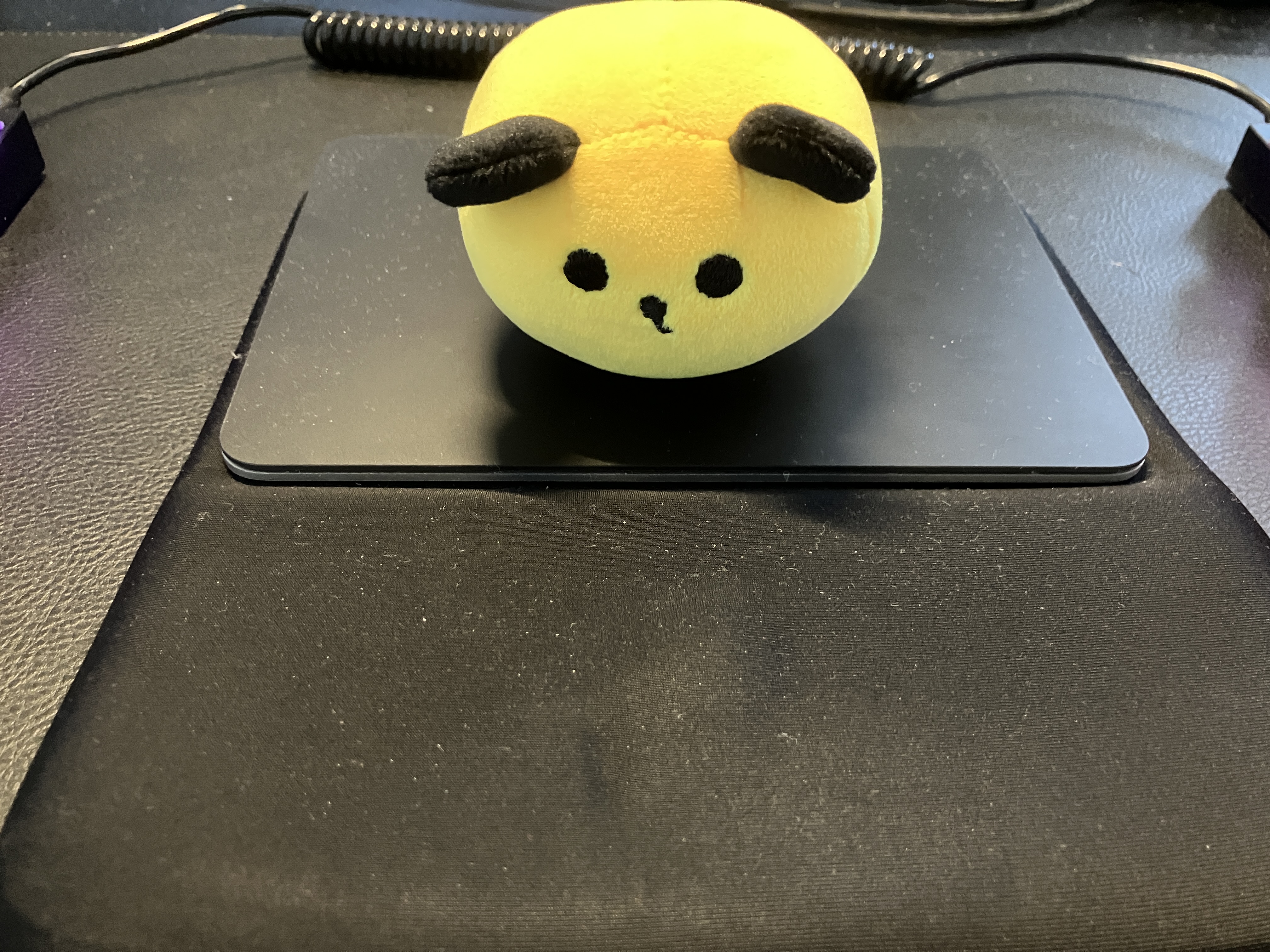 株式会社タイミーの公式キャラクター、タイミンのぬいぐるみがMacのトラックパッドの上に乗っている様子